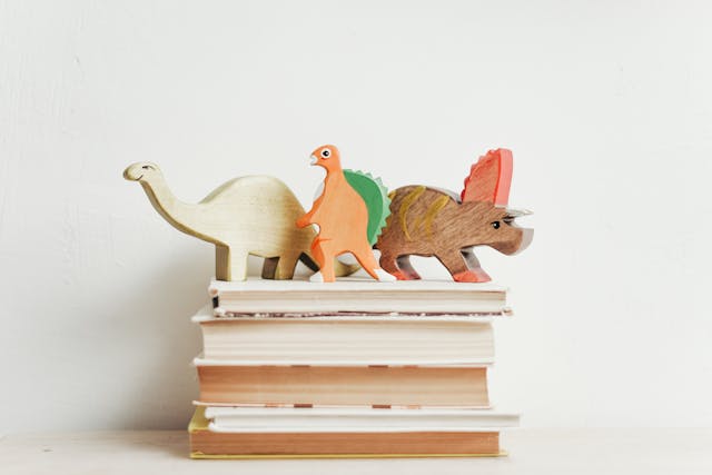 Une pile de livre avec des dinosaures en bois dessus : l'objectif est de présenter son histoire autrement